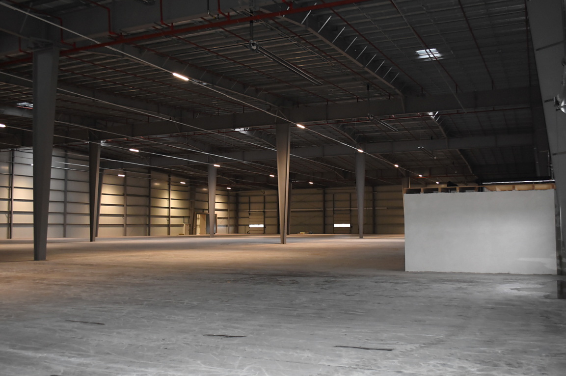 Freie Hallenfläche mit Stützen, LED-Beleuchtung und sichtbarer Sprinklertechnik